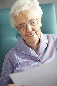 Senior Woman Relaxing In Chair Reading Letter