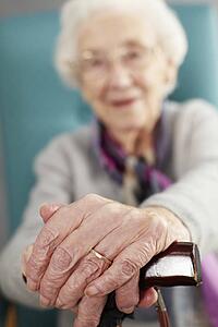 Senior Woman Relaxing In Chair Holding Walking Stick