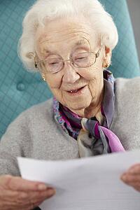 Senior Woman Relaxing In Chair Reading Letter