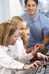 Girls using computers in class with teacher