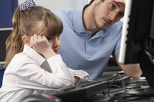 Unhappy teacher and girl using computer in class