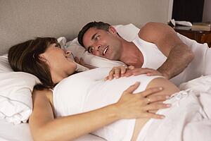 Pregnant woman and husband in bed