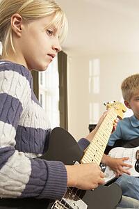 Boy and girl playing electric guitars at home