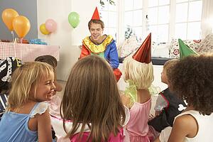 Young children eating jam tarts at birthday party
