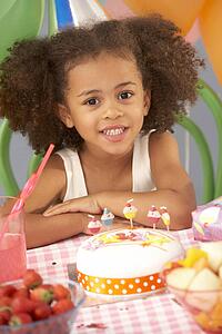 Young girl with birthday cake at party