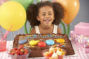 Young girl with birthday cake and gifts at party