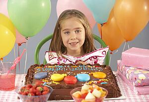 Young girl with birthday cake and gifts at party