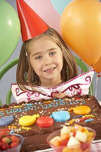 Young girl with birthday cake at party