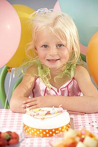 Young girl with birthday cake at party
