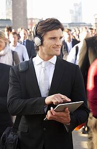 Male commuter in crowd with tablet and headphones