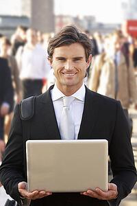 Male commuter in crowd using laptop