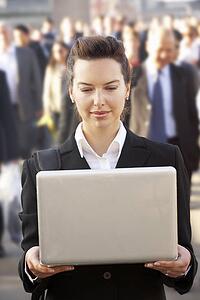 Female commuter in crowd using laptop