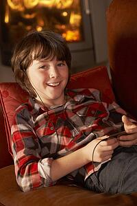 Young Boy Relaxing With MP3 Player By Cosy Log Fire