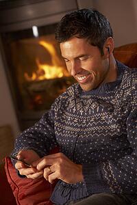 Middle Aged Man Using MP3 Player By Cosy Log Fire