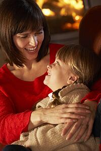 Mother And Daughter Relaxing On Sofa By Cosy Log Fire