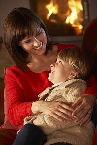Mother And Daughter Relaxing On Sofa By Cosy Log Fire