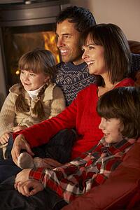 Family Relaxing Watching TV By Cosy Log Fire