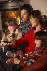 Family Relaxing Watching TV By Cosy Log Fire