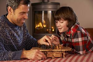 Father And Son Playing Chess By Cosy Log Fire