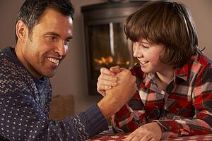 Father And Son Arm Wrestling By Cosy Log Fire