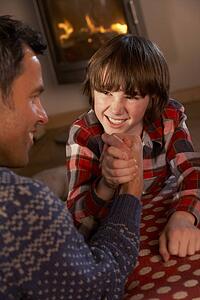Father And Son Arm Wrestling By Cosy Log Fire