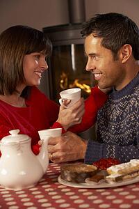Couple Enjoying Tea And Cake By Cosy Log Fire