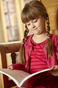 Young Girl Sitting On Wooden Seat Reading Book