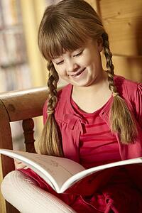 Young Girl Sitting On Wooden Seat Reading Book