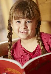Young Girl Sitting On Wooden Seat Reading Book