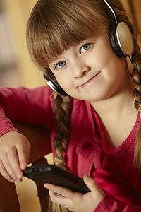Young Girl Sitting On Wooden Seat Listening To MP3 Player