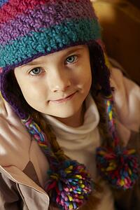Young Girl Sitting On Wooden Seat Wearing Warm Outdoor Clothes