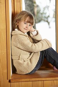 Young Girl Sitting On Window Ledge Looking At Snowy View
