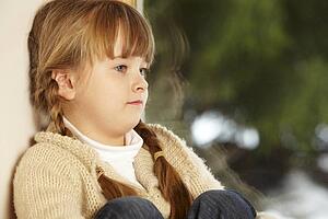Young Girl Sitting On Window Ledge Looking At Snowy View