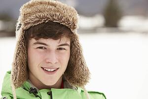 Portrait Of Teenage Boy In Snow Wearing Fur Hat