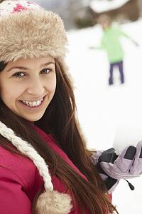 Teenage Couple Having Snowball Fight Wearing Fur Hats
