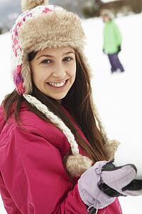 Teenage Couple Having Snowball Fight Wearing Fur Hats