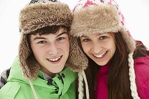 Portrait Of Teenage Couple In Snow Wearing Fur Hats