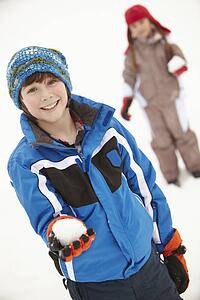 Two Young Children Having Snowball Fight Wearing Woolly Hats