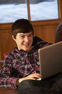 Teenage Boy Relaxing On Sofa With Laptop
