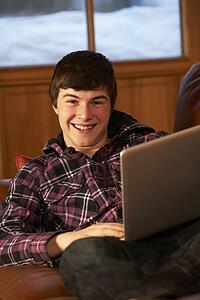 Teenage Boy Relaxing On Sofa With Laptop