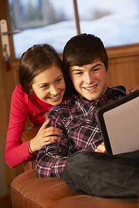 Teenage Couple Relaxing On Sofa With Tablet Computer