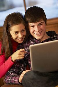 Teenage Couple Relaxing On Sofa With Laptop