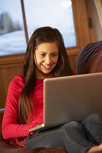 Teenage Girl Relaxing On Sofa With Laptop