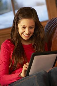 Teenage Girl Relaxing On Sofa With Tablet Computer