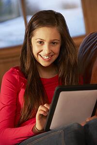 Teenage Girl Relaxing On Sofa With Tablet Computer