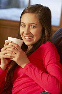 Teenage Girl Relaxing On Sofa With Hot Drink