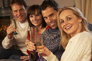 Group Of Middle Aged Couples Sitting On Sofa With Champagne