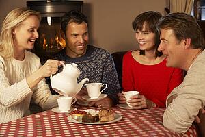 Group Of Middle Aged Couples Enjoying Tea And Cake Together