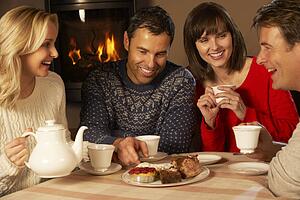 Group Of Middle Aged Couples Enjoying Tea And Cake Together
