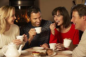 Group Of Middle Aged Couples Enjoying Tea And Cake Together